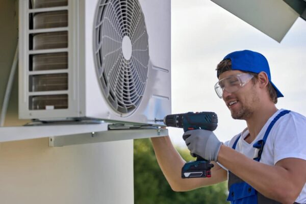 Caucasian worker installs outer metal case air conditioner with screwdriver AC Installation Service Near You MetroHandz