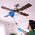 Cleaner dusting ceiling fan in living room